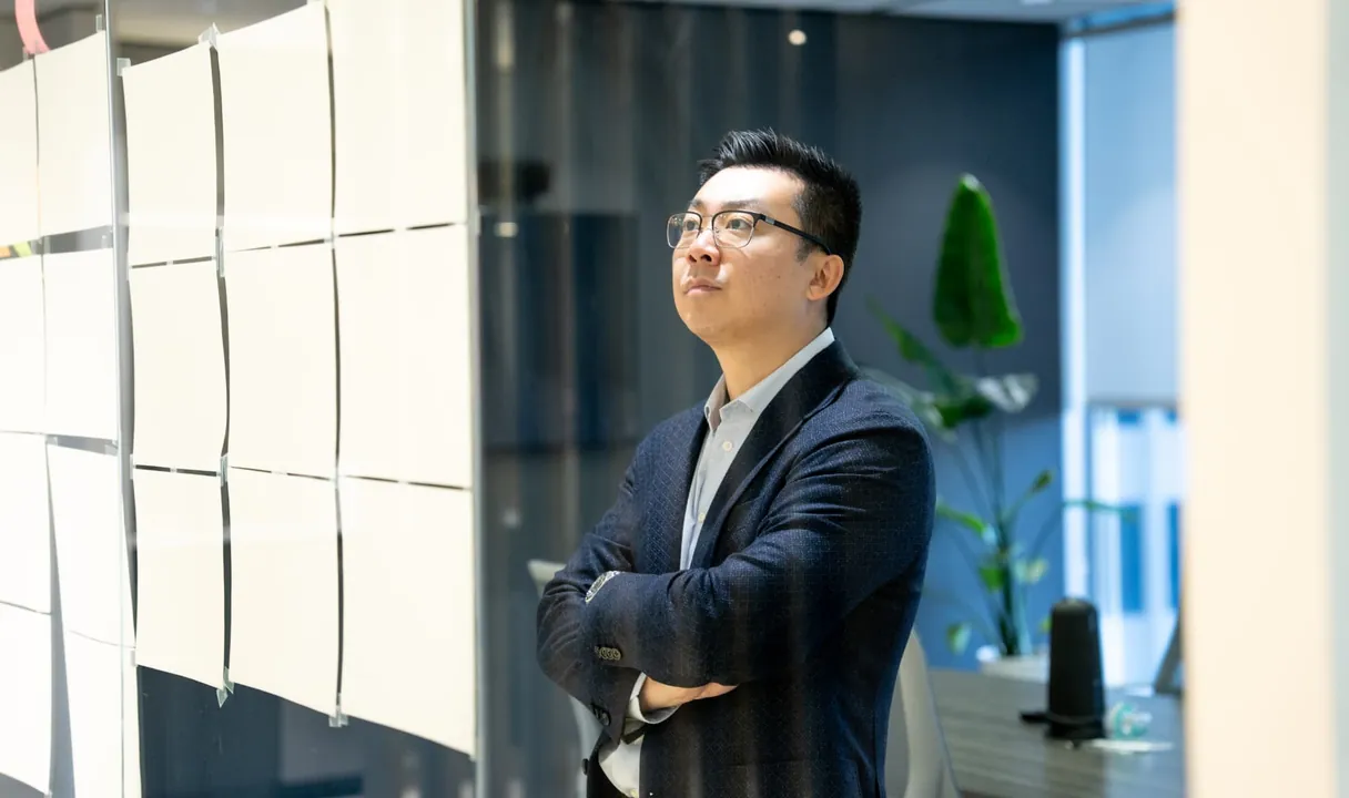 A Motiv advisor standing with arms crossed, reviewing cards on a glass office wall